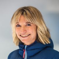 Smilende kvinne, Gina Kveen, med blondt hår iført blå jakke.