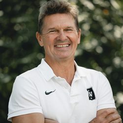 Fredrik Aukland, selvsikker mann i hvit poloskjorte, armene i kors, med et varmt smil utendørs.