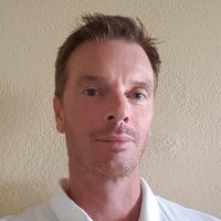 Et nærbilde av Geir Myklebust med et velstelt utseende, med et lett smil og oppmerksomt blikk, fanget mot en nøytral bakgrunn.