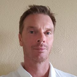 Et nærbilde av Geir Myklebust med et velstelt utseende, med et lett smil og oppmerksomt blikk, fanget mot en nøytral bakgrunn.