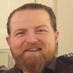 En skjeggete mann med et vennlig smil, poserer på et uformelt bilde av Lasse Hauser.