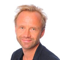 En selvsikker mann med et vennlig smil, kort blondt hår og skjeggstubber, iført mørk fritidsjakke mot hvit bakgrunn er Niclas Magnusson.