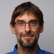 Portrett av Oddvar Taksdal, en smilende mann med briller.