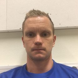 En mann med kort, piggete hår iført blå skjorte som sitter foran en off-white vegg med et nøytralt uttrykk er Robert Andre Honningdalsnes.