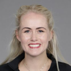Caroline Westerheim, en selvsikker kvinne med et strålende smil og blondt hår bundet tilbake, iført en svart topp og et subtilt halskjede.