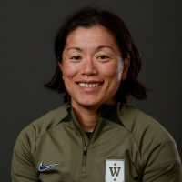 Et portrett av Emi Uchibayashi smilende med kort hår, iført en sportsjakke med glidelås med synlig logo på venstre side.
