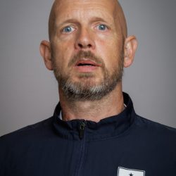 En mann med skjegg og et kontemplativt uttrykk som ser oppover.