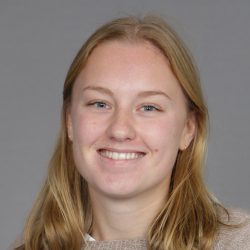 En smilende ung kvinne med blondt hår og blå øyne, kledd i en lys topp, poserer for et portrett mot ensfarget bakgrunn, heter Ingvild Torgersen.