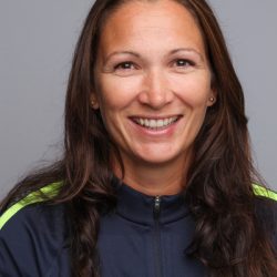 En smilende kvinne med langt hår, iført sporty antrekk, mot nøytral bakgrunn identifiseres som Kristine Wiig Skarlund.