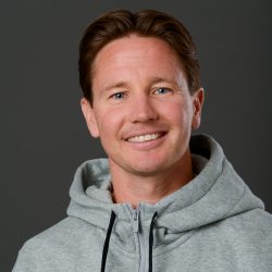 Portrett av en smilende mann med ingefært hår, iført en grå hettegenser mot en grå bakgrunn. Kjent som Martin Flismyren.
