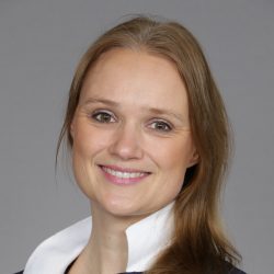 Profesjonelt hodebilde av Siri K. Gjerde, en smilende kvinne med langt hår, kledd i forretningsantrekk med hvit krage.