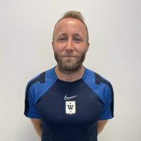 Michael Rosenberg, mann med skjegg i en blå sportstrøye poserer på et bilde mot en vanlig bakgrunn.