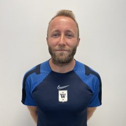 Michael Rosenberg, mann med skjegg i en blå sportstrøye poserer på et bilde mot en vanlig bakgrunn.