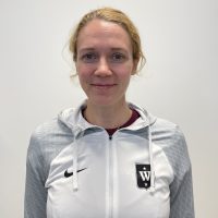 En smilende kvinne, Ida Sandin, iført en lysegrå sportsjakke med klubbemblem på venstre side.