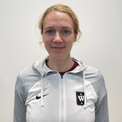 En smilende kvinne, Ida Sandin, iført en lysegrå sportsjakke med klubbemblem på venstre side.
