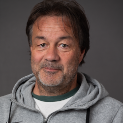 Portrett av Vegard Skogheim, en middelaldrende mann med et innholdsuttrykk, med små skjeggstubber og en uformell grå hettegenser.